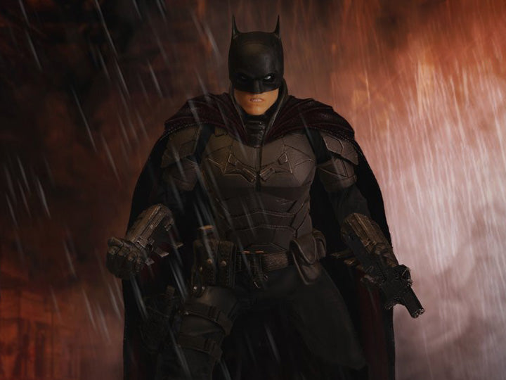 The Batman is outfitted in a screen-accurate armored Batsuit with chest insignia. The costume features an integrated posing wire in the cape, utility belt, a thigh pouch, and two vambrace. Batman comes complete with four head portraits including an unmasked Bruce Wayne portrait, all featuring the likeness of actor Robert Pattinson. Equipped with multiple Batarangs, sticky bombs, handcuffs, grapple launcher, and smoke bombs, Batman fights crime in the wet and grimy streets of Gotham.